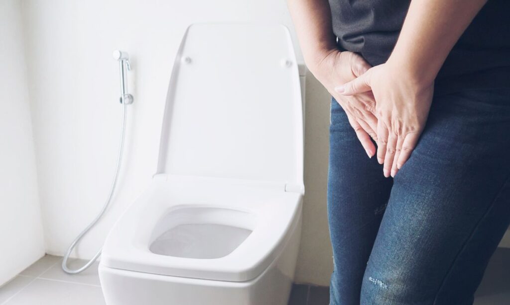 A man holding a crotch near the toilet bowl showing sign of being painful.